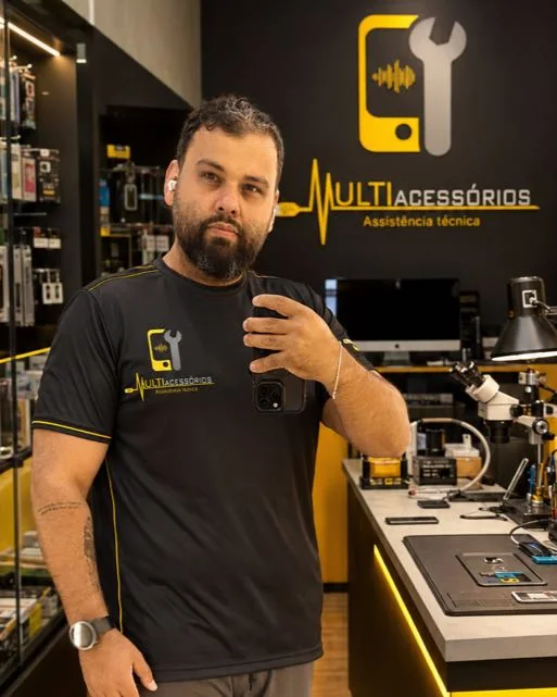 Varley, dono da Multi Acessórios, na loja ao lado da bancada de consertos, com a camiseta da marca